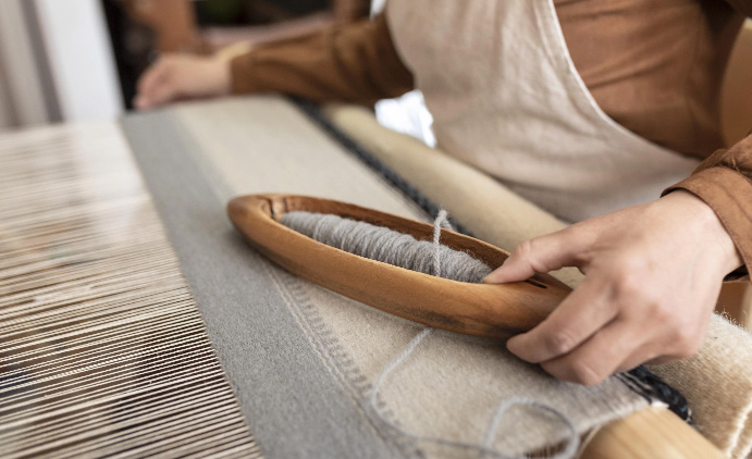 Person weaving at a loom.