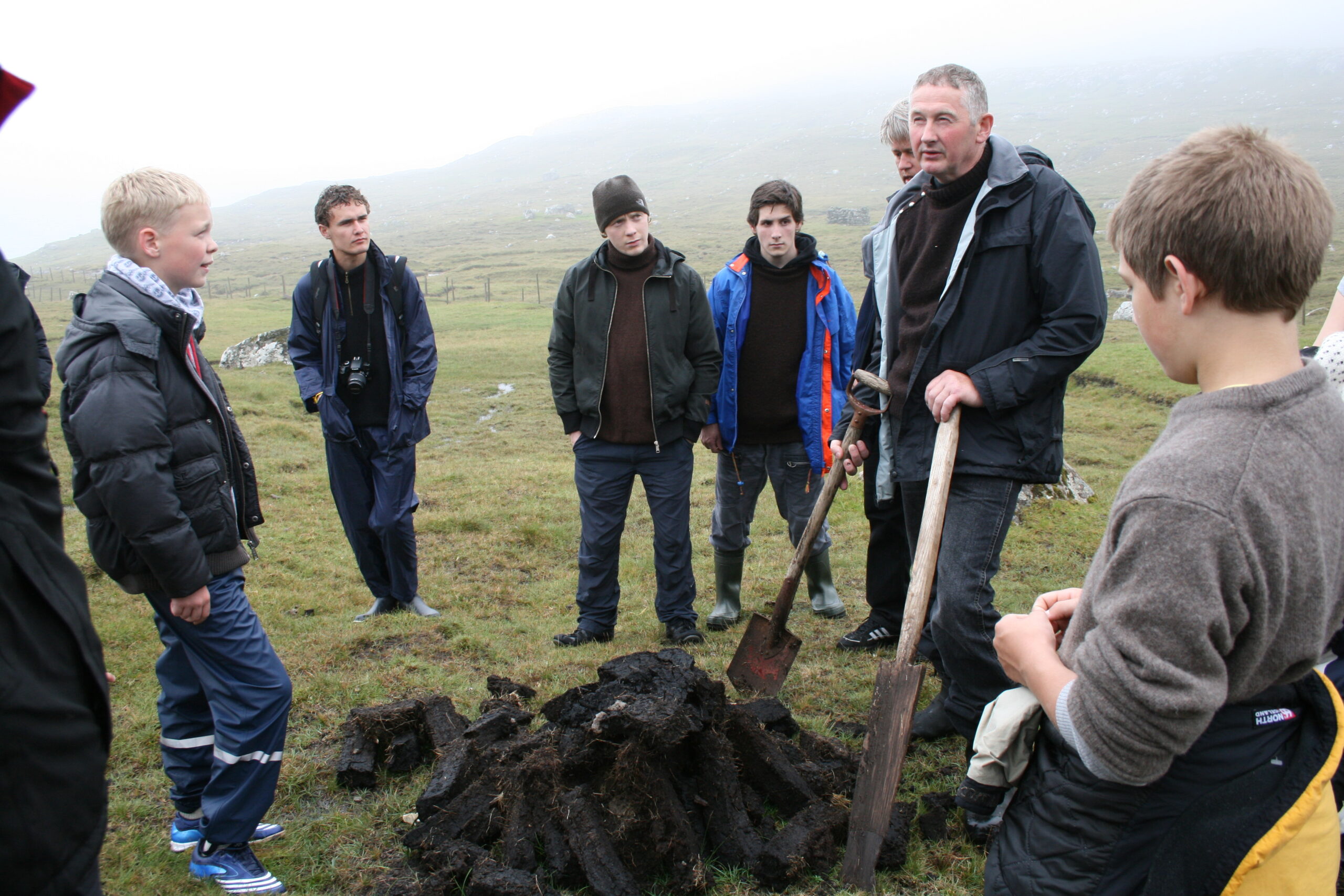 People on a field around an instructor explaining about peat collecting.