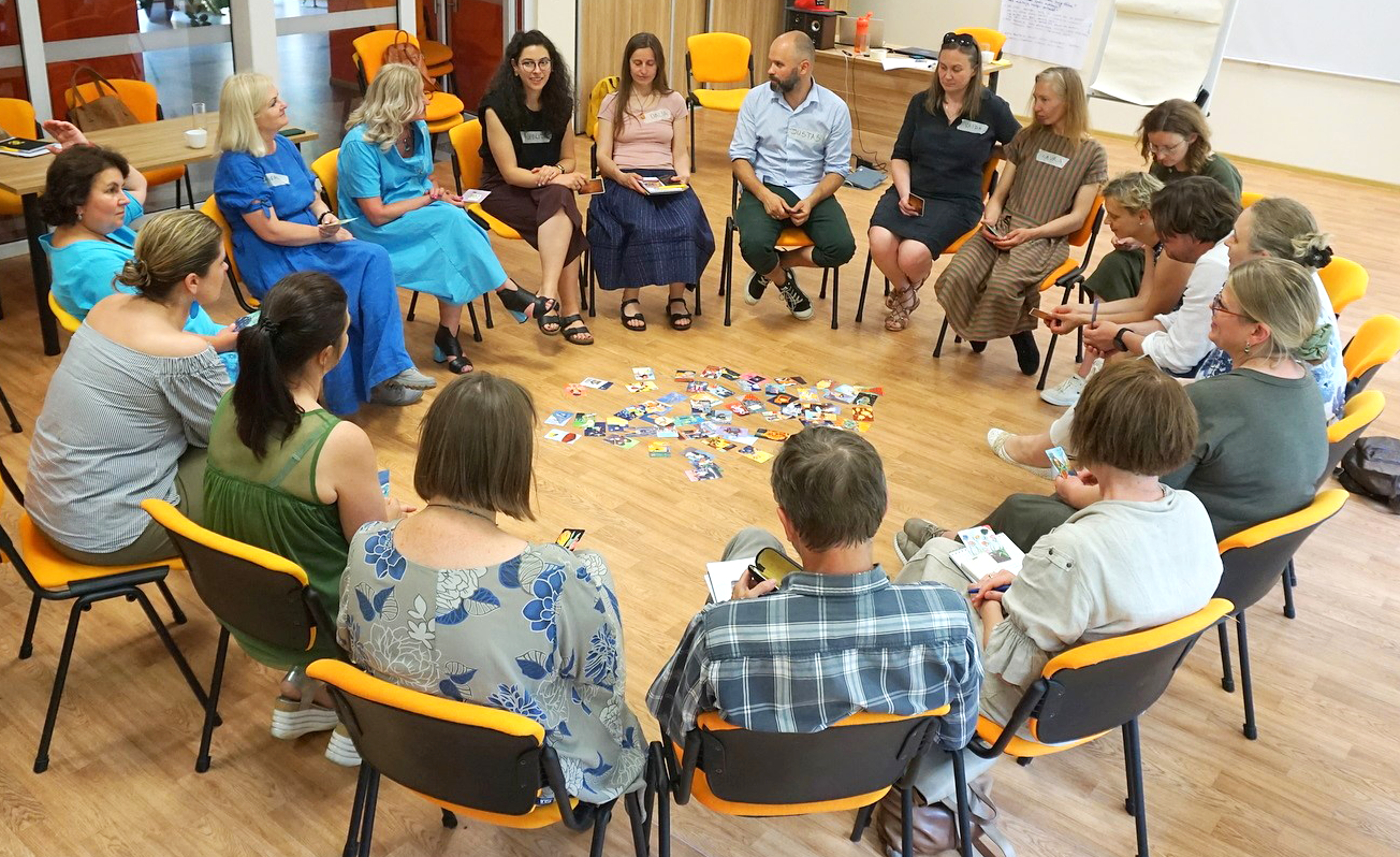 People are sitting on chairs forming a circle and discuss the cards that are placed on the floor.